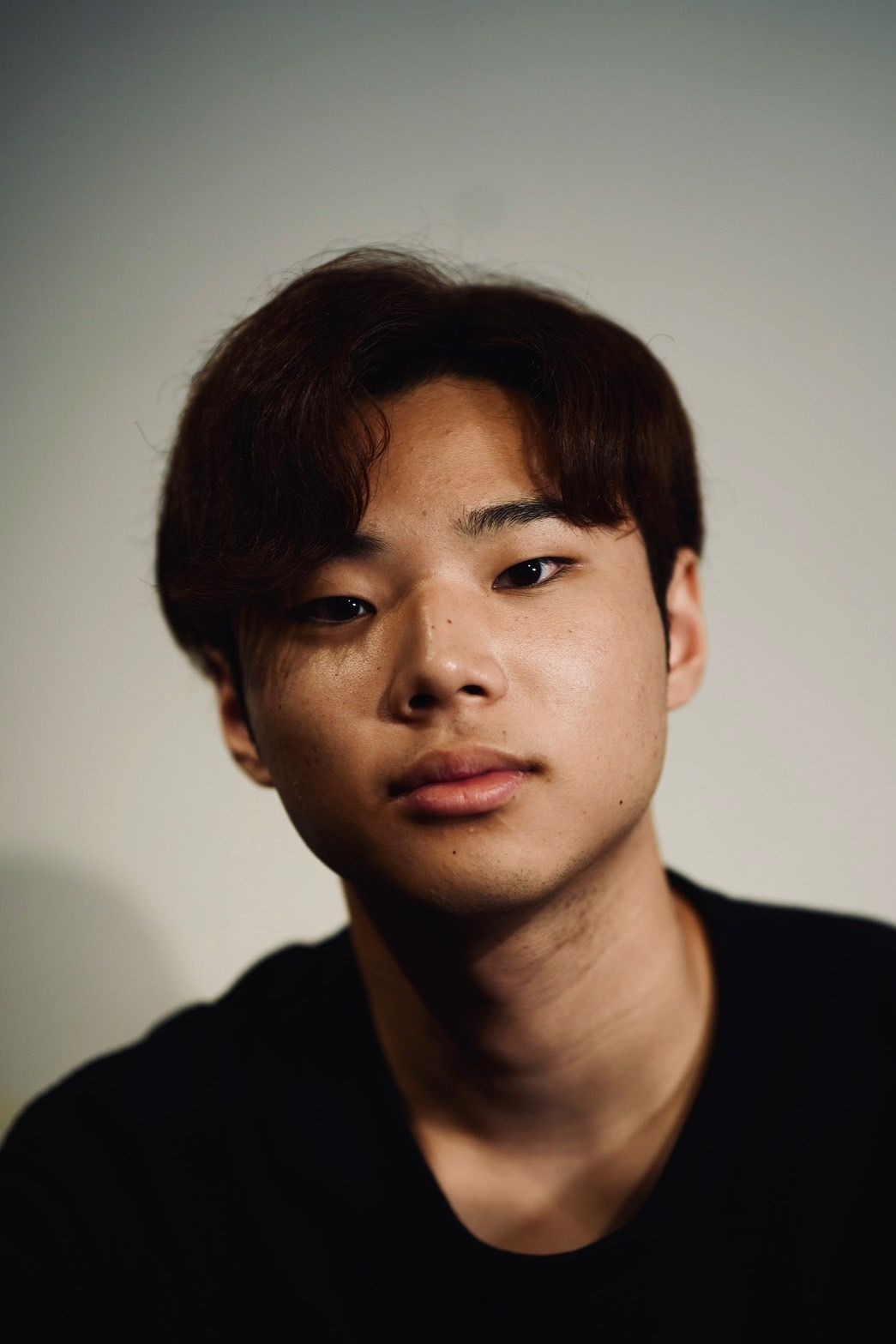 Portrait of a person with short brown hair and a neutral expression against a plain background.